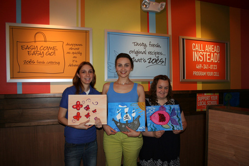 April Vander Haar, Ekaterina Konovalova and Melissa Yassini displaying children's paintings at Zoes Kitchen